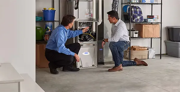 Technician explaining furnace system to a homeowner in a utility room